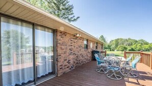 Un patio couvert avec un mur en briques, des portes-fenêtres coulissantes et du mobilier d’extérieur.