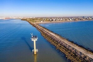 A coastal area with a lighthouse, a breakwater, and a residential area in the background. - 🌴Surfside Paradise#3-amazing views,golfcart🌴 (Surfside Beach)