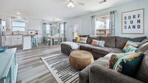 A modern living room with a grey sofa, a woven ottoman, and a striped rug. - 🌴Surfside Paradise#3-amazing views,golfcart🌴 (Surfside Beach)