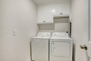A laundry room with two white dryers and a cabinet above them.