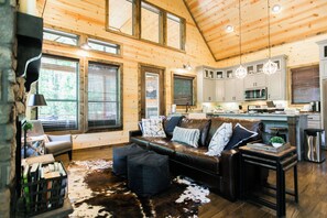 A spacious living room with a leather sofa, a cowhide rug, and a wooden ceiling.