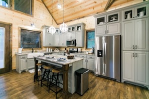 A modern kitchen with wooden walls, stainless steel appliances, and a central island with stools.