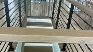 A modern interior with a wooden staircase, a kitchen area, and a dining space. - Across The Street From The Beach, Private Beach & Pool Access, Elevator (Holden Beach)