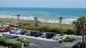 A parking lot with cars and a beach in the background. - Across The Street From The Beach, Private Beach & Pool Access, Elevator (Holden Beach)