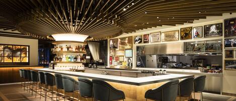 A modern bar area with a central island, bar stools, and a variety of liquor bottles.