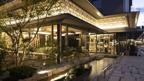 A modern building with a glass facade, a water feature, and a stone pathway. - Cross Hotel Kyoto (Kyoto)