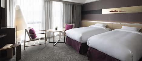A hotel room with two beds, a desk, a chair, and a large window with curtains.