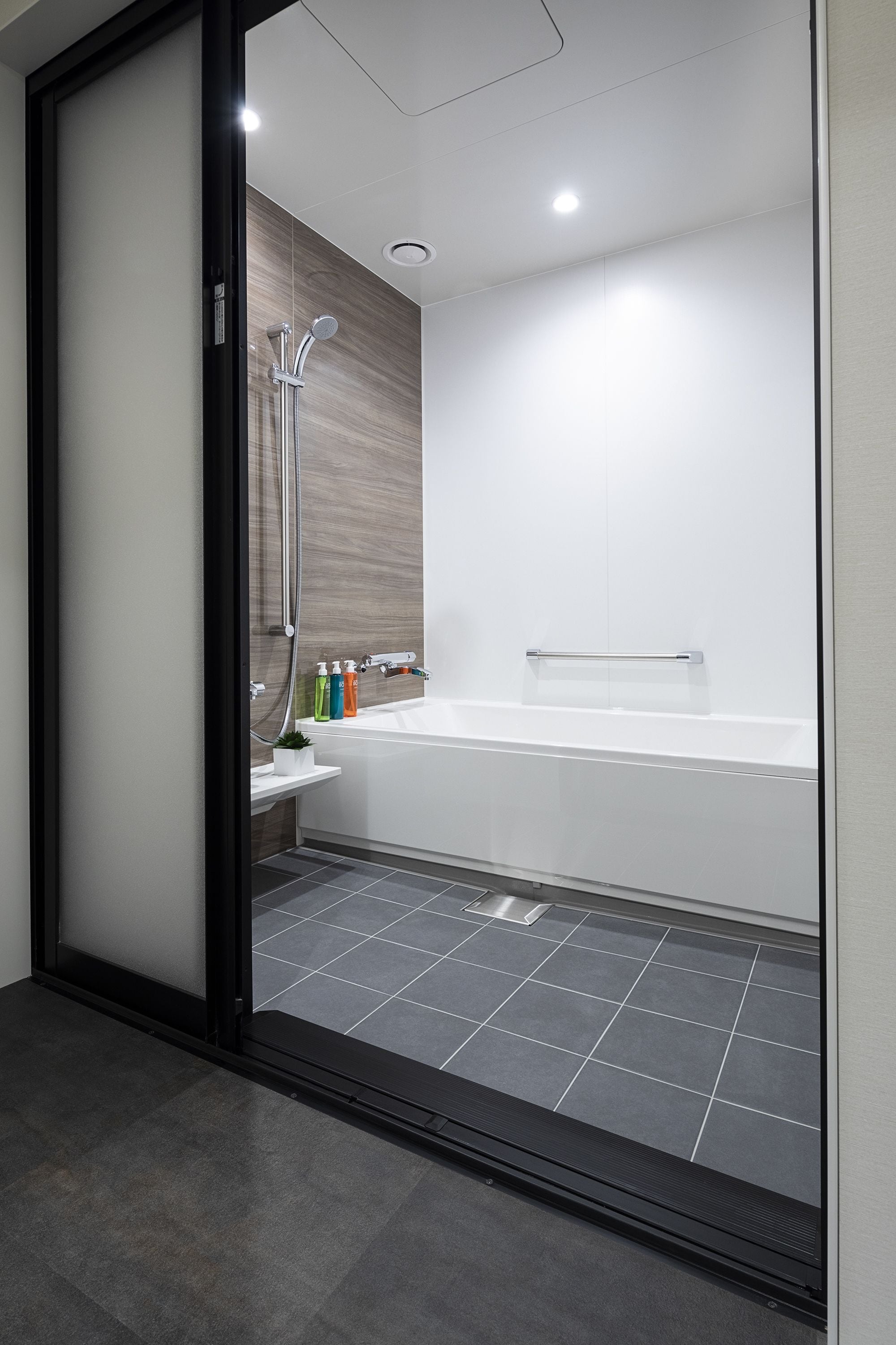 Un baño moderno con cabina de ducha de vidrio, una bañera y un estante pequeño con artículos de aseo.