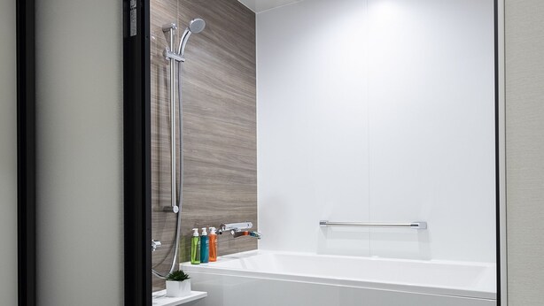 A modern bathroom with a glass shower enclosure, a bathtub, and a small shelf with toiletries. - Cross Hotel Kyoto (Kyoto)