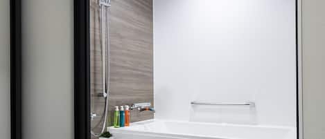 Un baño moderno con cabina de ducha de vidrio, una bañera y un estante pequeño con artículos de aseo.