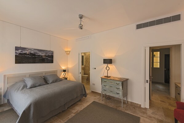 Un dormitorio con cama, lámparas de noche, cómoda y ventilador de techo.