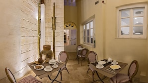 A dining area with a brick wall, a large vase, and a table set for four with chairs. - The Snop House (Senglea)