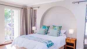 A bedroom with a large bed, two bedside tables, and a view of the outdoors.