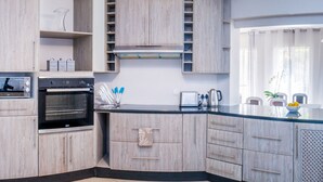A modern kitchen with wooden cabinets, a built-in oven, and a large window with curtains.
