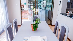 A dining table set with chairs, a potted plant, and a white table runner.