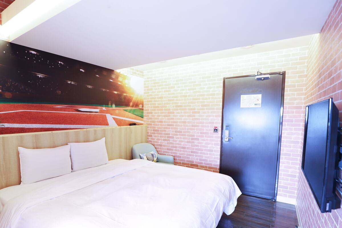Una habitación de hotel con cama, una silla, una puerta y una televisión.