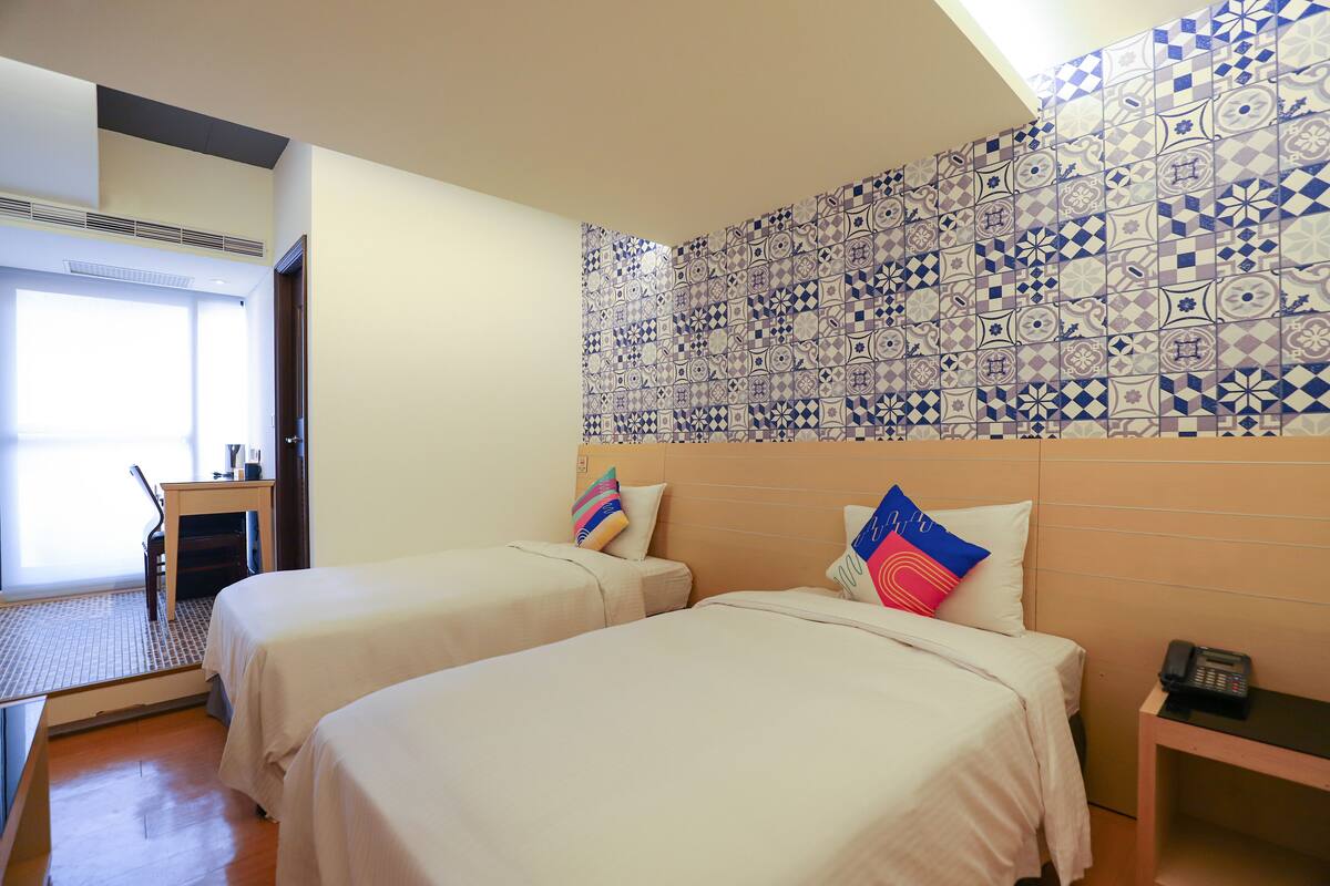 Habitación de hotel con dos camas, un escritorio y una pared con diseño.