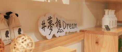 Een houten plank met een bord waarop '#dream' staat en een kleine potplant.