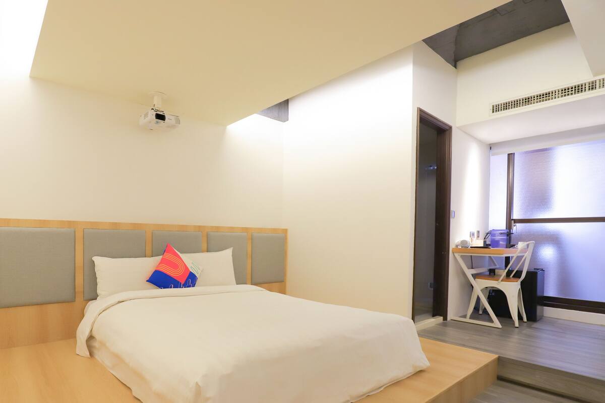 Una habitación de hotel con una cama, un escritorio y una silla.
