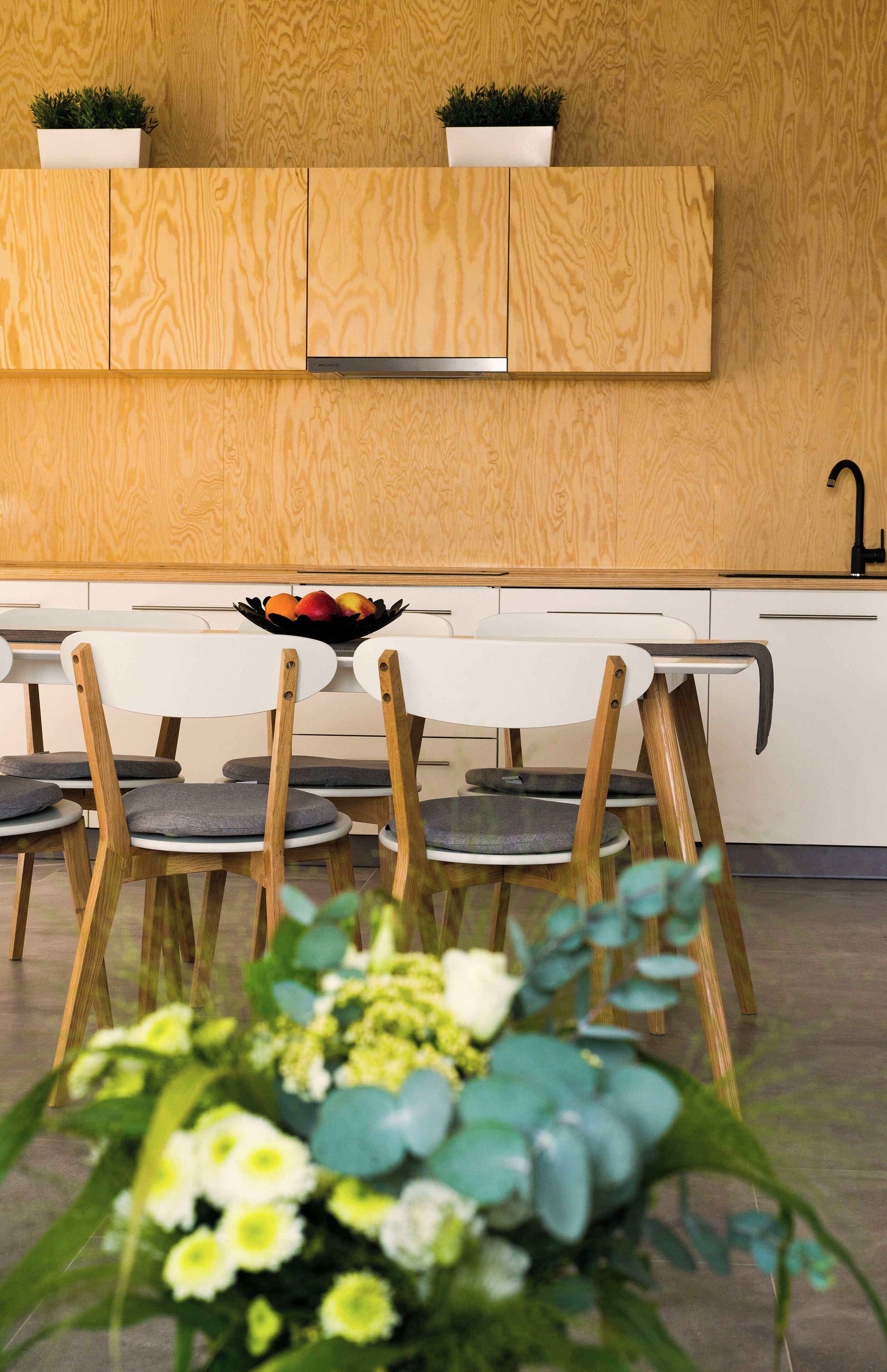 A modern kitchen with wooden cabinets, a white countertop, and a black faucet.