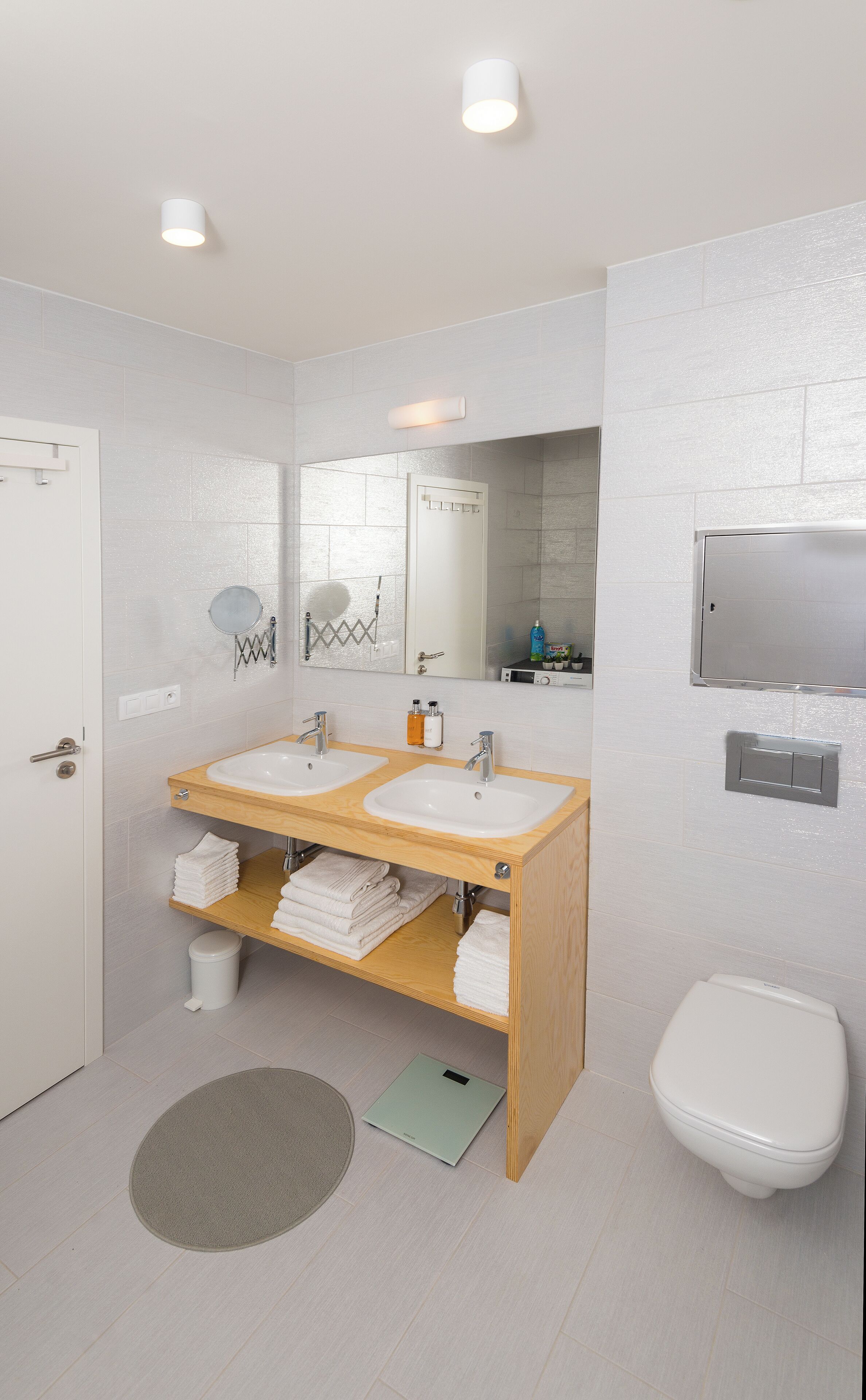 A modern bathroom with two sinks, a mirror, a toilet, and a shower area.