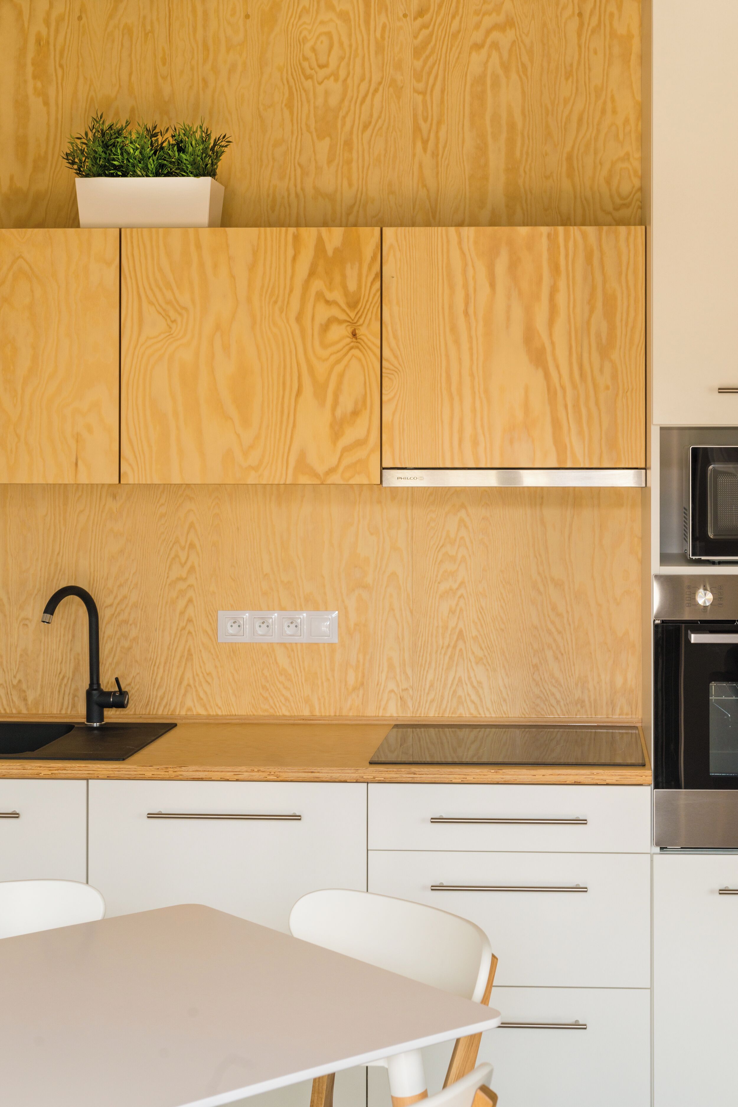 A modern kitchen with wooden cabinets, a stainless steel sink, and a built-in oven.