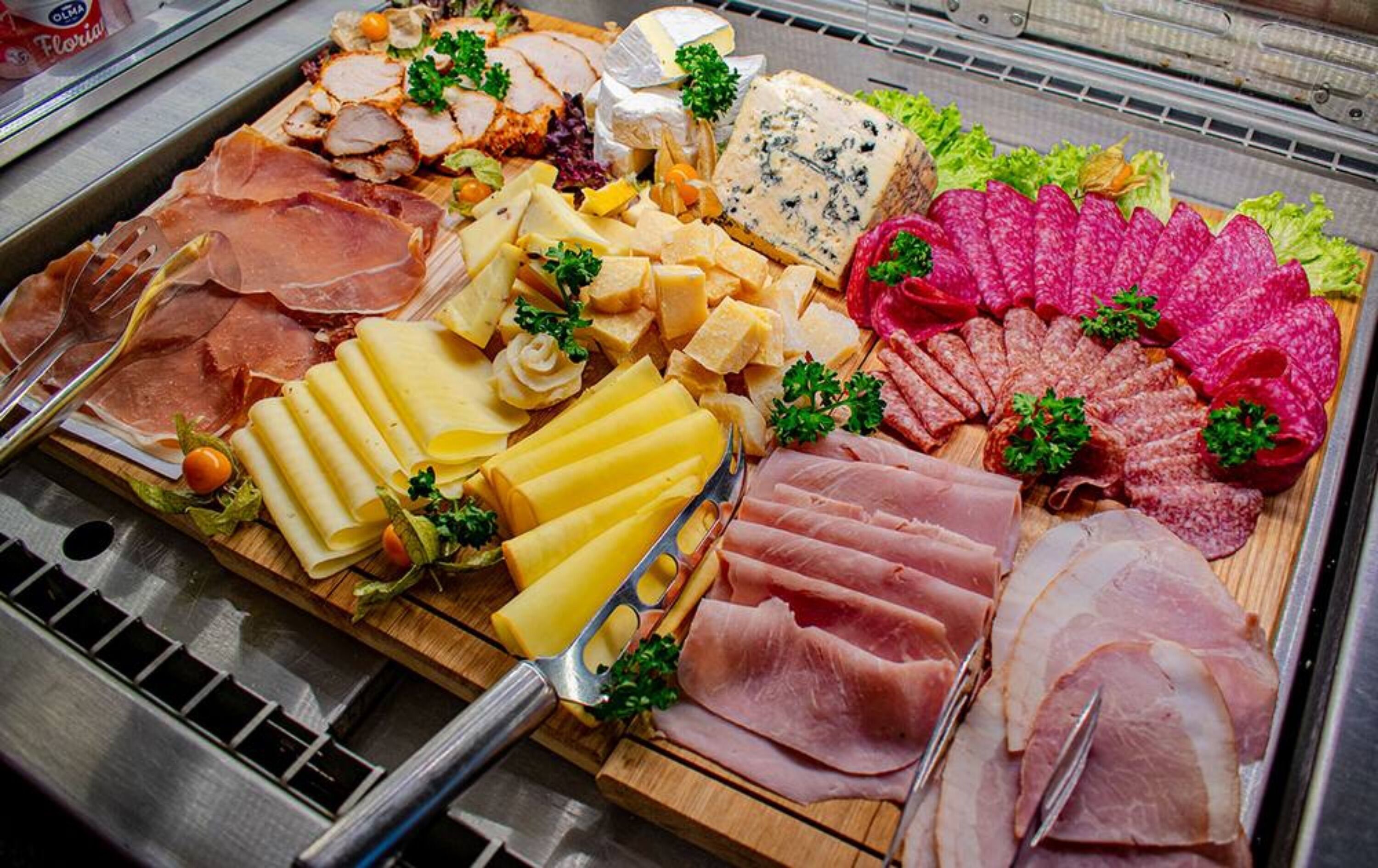 Una tabla de quesos y embutidos con diversos tipos de carne, queso y guarniciones.
