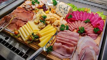 Una tabla de quesos y embutidos con diversos tipos de carne, queso y guarniciones.