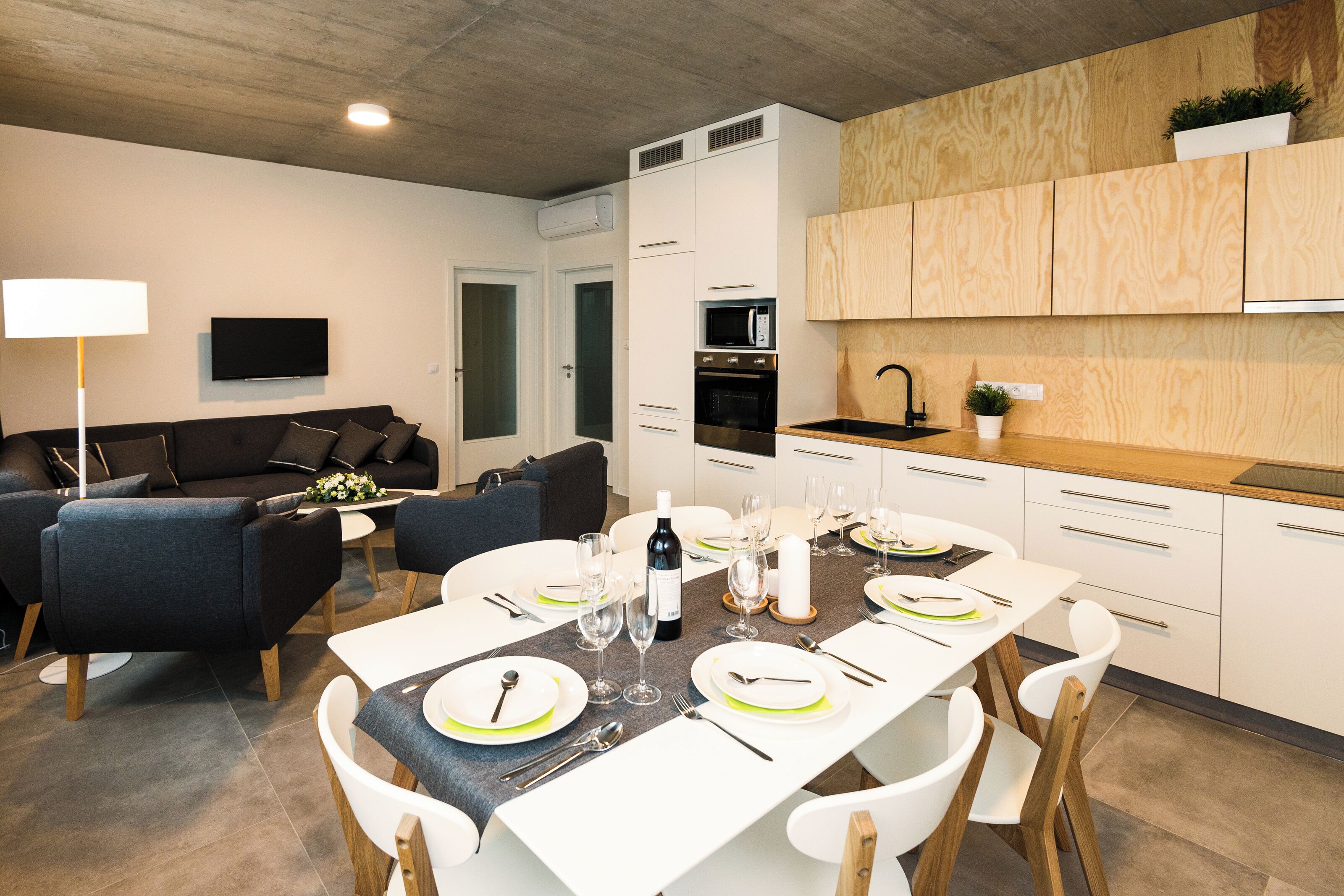 Una cocina moderna con armarios blancos, una encimera de madera y un microondas integrado.