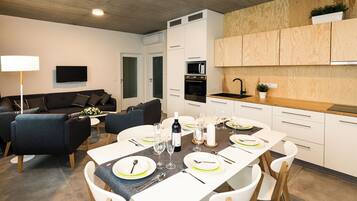 Una cocina moderna con armarios blancos, una encimera de madera y un microondas integrado.