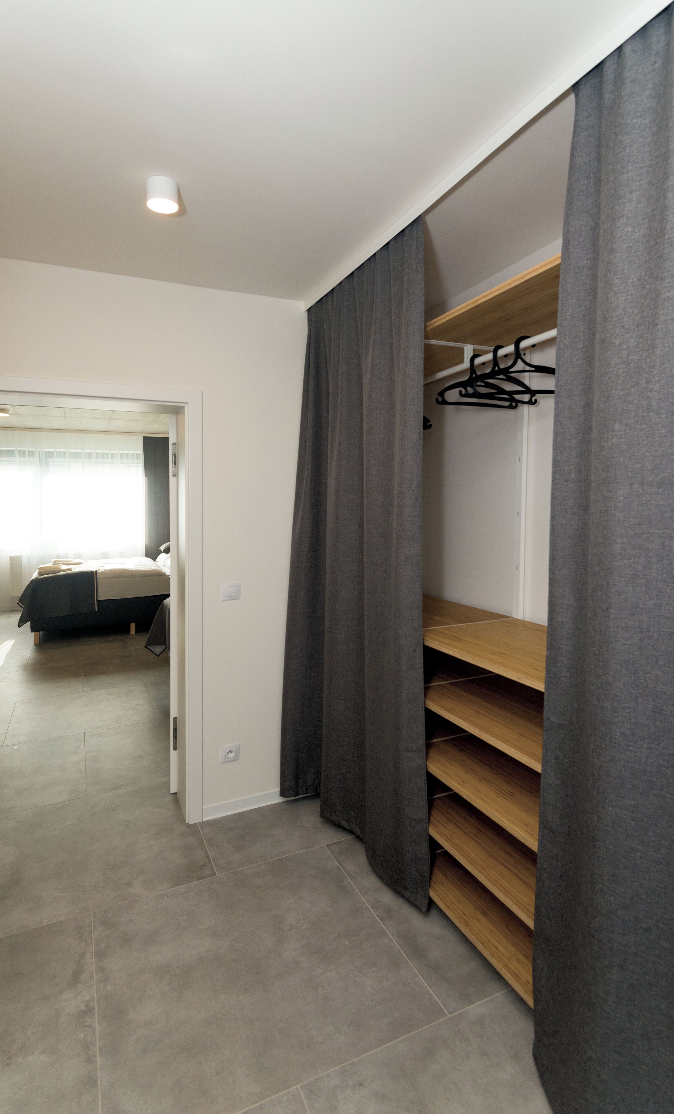A bedroom with a bed, a wardrobe, and a closet with shelves.