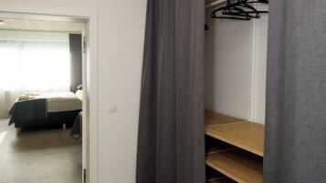 A bedroom with a bed, a wardrobe, and a closet with shelves.