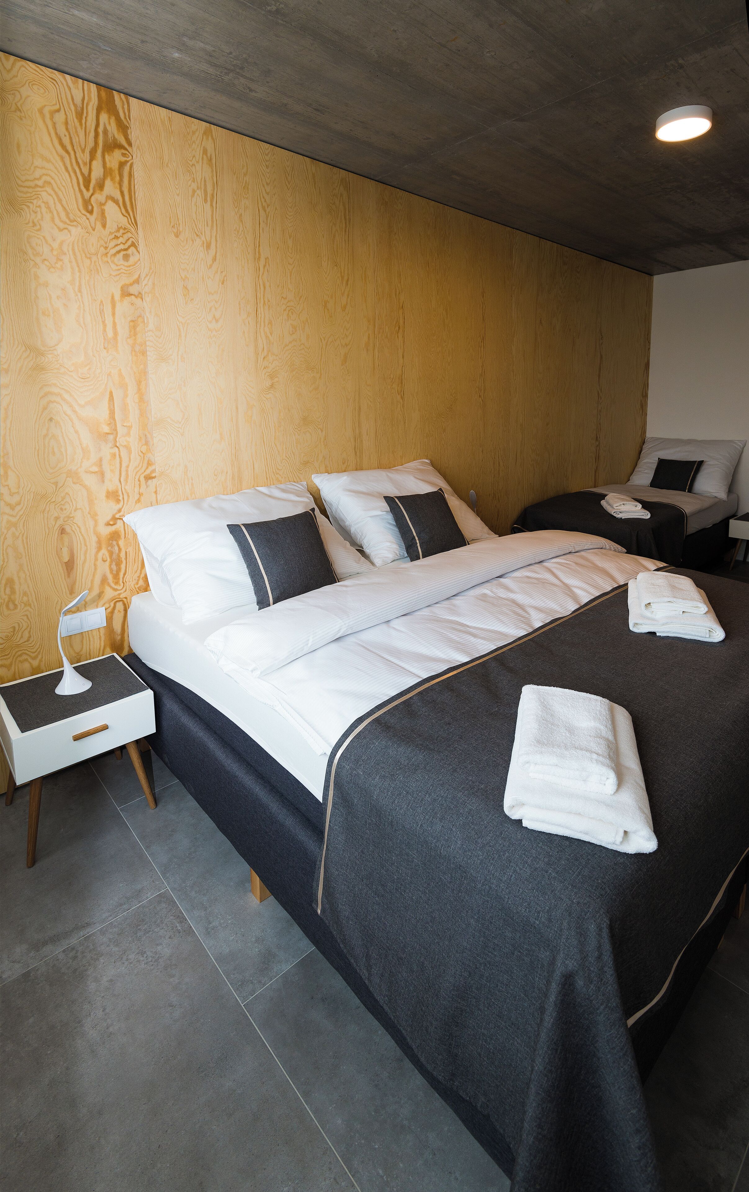 Una habitación de hotel moderna con una cama grande, dos mesitas de noche y una pared de madera decorativa.