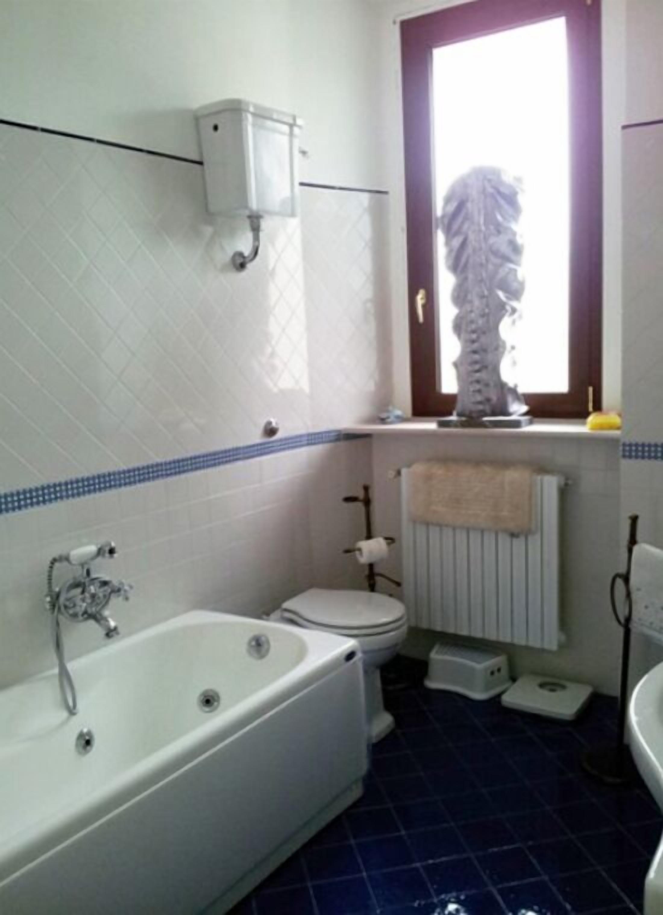 Un baño con bañera, inodoro y ventana.