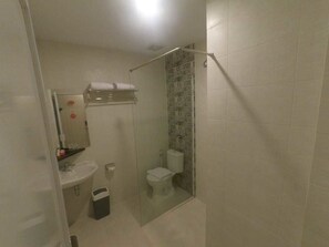A bathroom with a shower, toilet, sink, and a towel rack. - Front One Boutique Brani Solo (Surakarta)