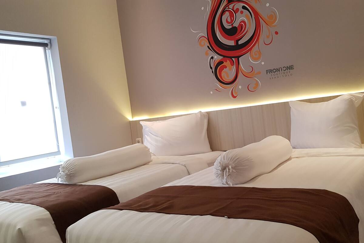 Une chambre d’hôtel avec deux lits, une œuvre d’art décorative au mur, une table de chevet avec un téléphone et une fenêtre avec des stores.