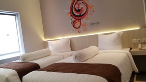 A hotel room with two beds, a decorative wall art piece, a bedside table with a phone, and a window with blinds. - Front One Boutique Brani Solo (Surakarta)