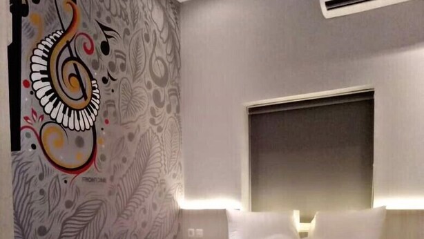 Une chambre d’hôtel moderne avec un grand lit, une tête de lit dotée d’un éclairage intégré et une fresque murale décorative.