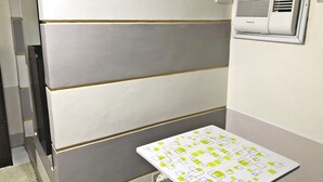 Une pièce avec un mur aux tons de gris et de blanc, un tableau blanc orné de formes géométriques et un climatiseur installé à la fenêtre.