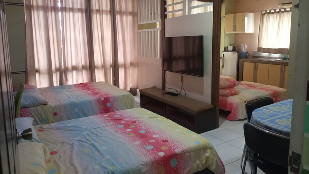 Une chambre d’hôtel avec deux lits, une télévision, un bureau et une kitchenette.