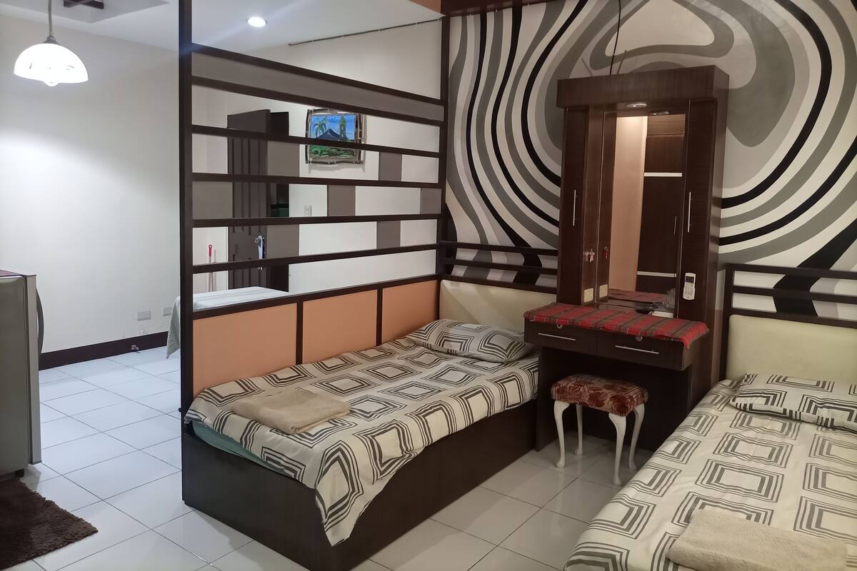 A bedroom with a bed, a bench, a small stool, a mirror, and a wardrobe.