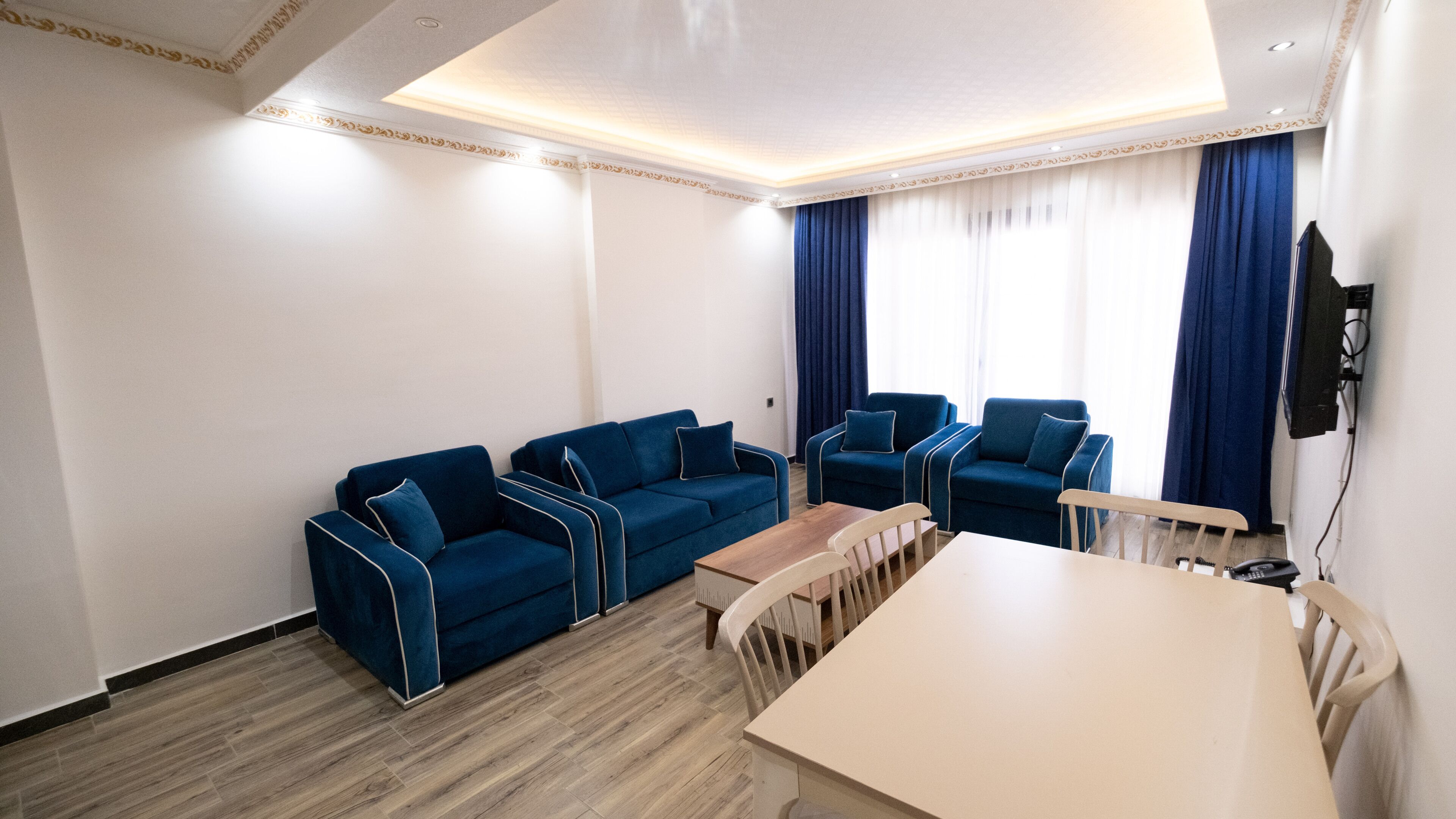Una sala de estar moderna con un juego de sofá, una mesa de comedor y un televisor montado en la pared.