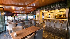 Un restaurante con barra, techo de madera y suelo de mármol.