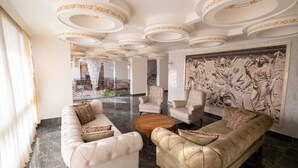 Un lobby lujoso con suelo de mármol, muebles elegantes y diseños ornamentales en el techo.