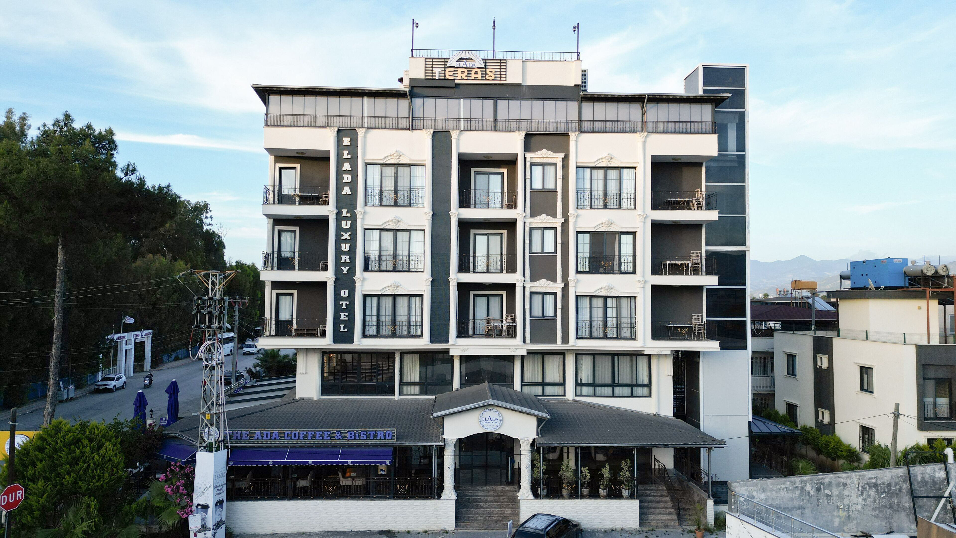 A multi-story hotel with a central entrance, balconies, and a coffee shop at the ground level.
