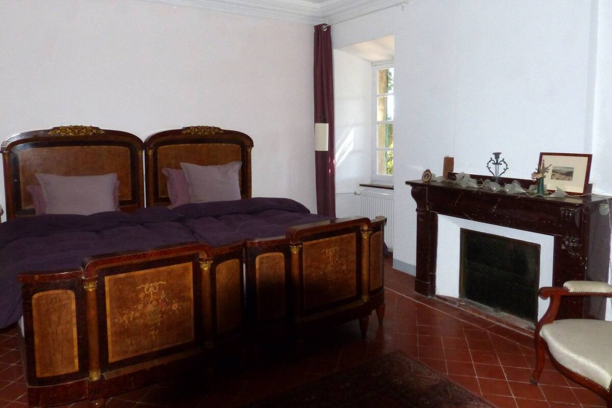 Een slaapkamer met een groot bed, een open haard en een stoel.