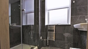 Une salle de bain moderne dotée d’une douche à parois de verre, d’un lavabo intégré et d’un porte-serviettes.