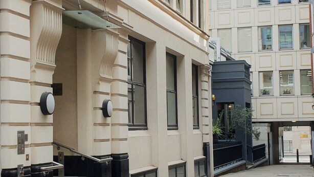 Un bâtiment à la façade classique, doté de grandes fenêtres et d’une entrée fermée par un portail.