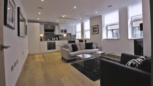 Un salon moderne avec un canapé, une table basse et une cuisine en arrière-plan.