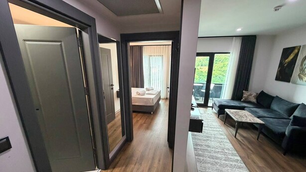 A modern living room with a sofa, a coffee table, and a view of the outdoors. - Dedehan Otel (Arsin)